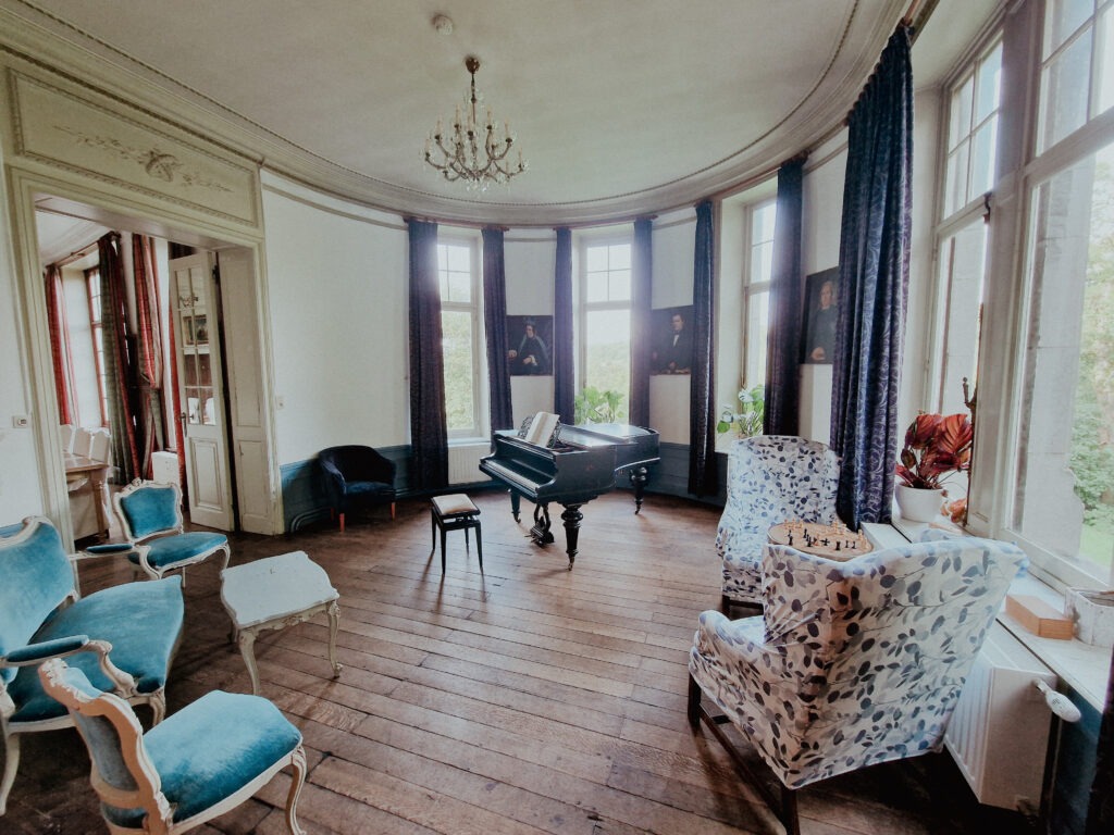 Music room of Blier Castle with period armchairs and a piano.