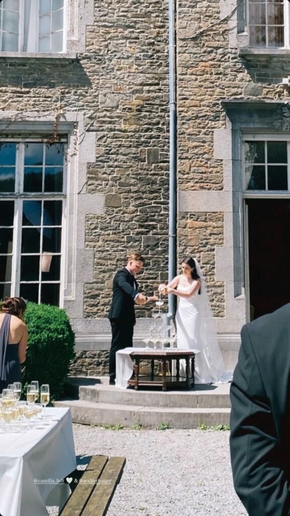 Uw verblijf in het Château de Blier 3 Uw Verblijf in Château de Blier : Een gelukkig pasgetrouwd stel serveert champagne in gestapelde glazen op de binnenplaats van kasteel Blier tijdens hun receptie. Screenshot van Instagram.