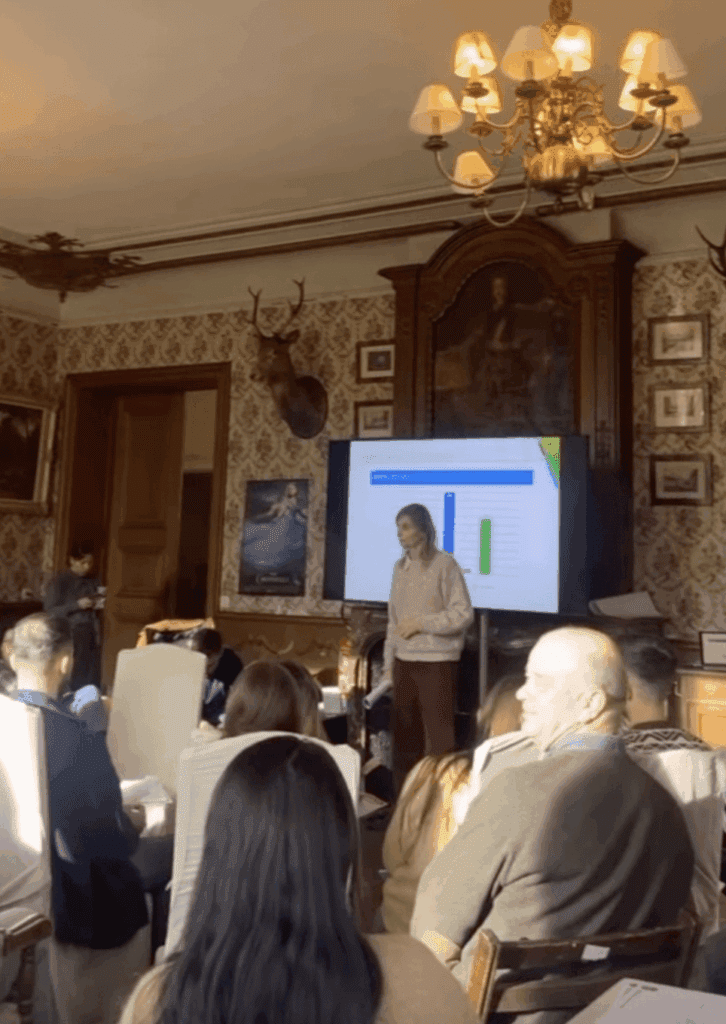 Uw verblijf in het Château de Blier 4 Uw Verblijf in Château de Blier : Een teambuildingsessie in het Château de Blier, waar iemand numerieke gegevens presenteert op een projectiescherm voor zijn of haar team, in een rijk versierde en fraai ingerichte zaal.