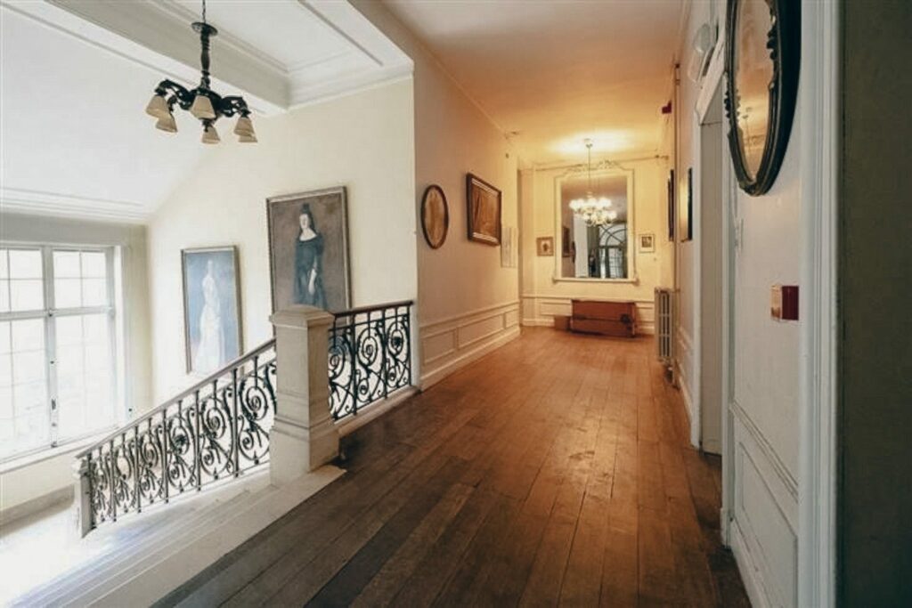 Accueil 3 Le hall du château de Blier donne accès aux chambres, dotées d'un parquet en bois bien entretenu, d'un lustre, de miroirs et de tableaux d'époque pour un hébergement de charme.