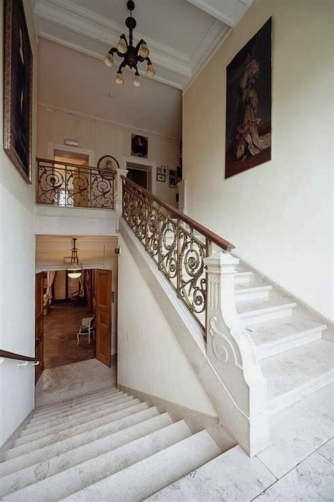 Découvrez le Château de Blier 5 Escalier du château de Blier, avec des marches en marbre blanc, un lustre et un grand tableau d'époque.